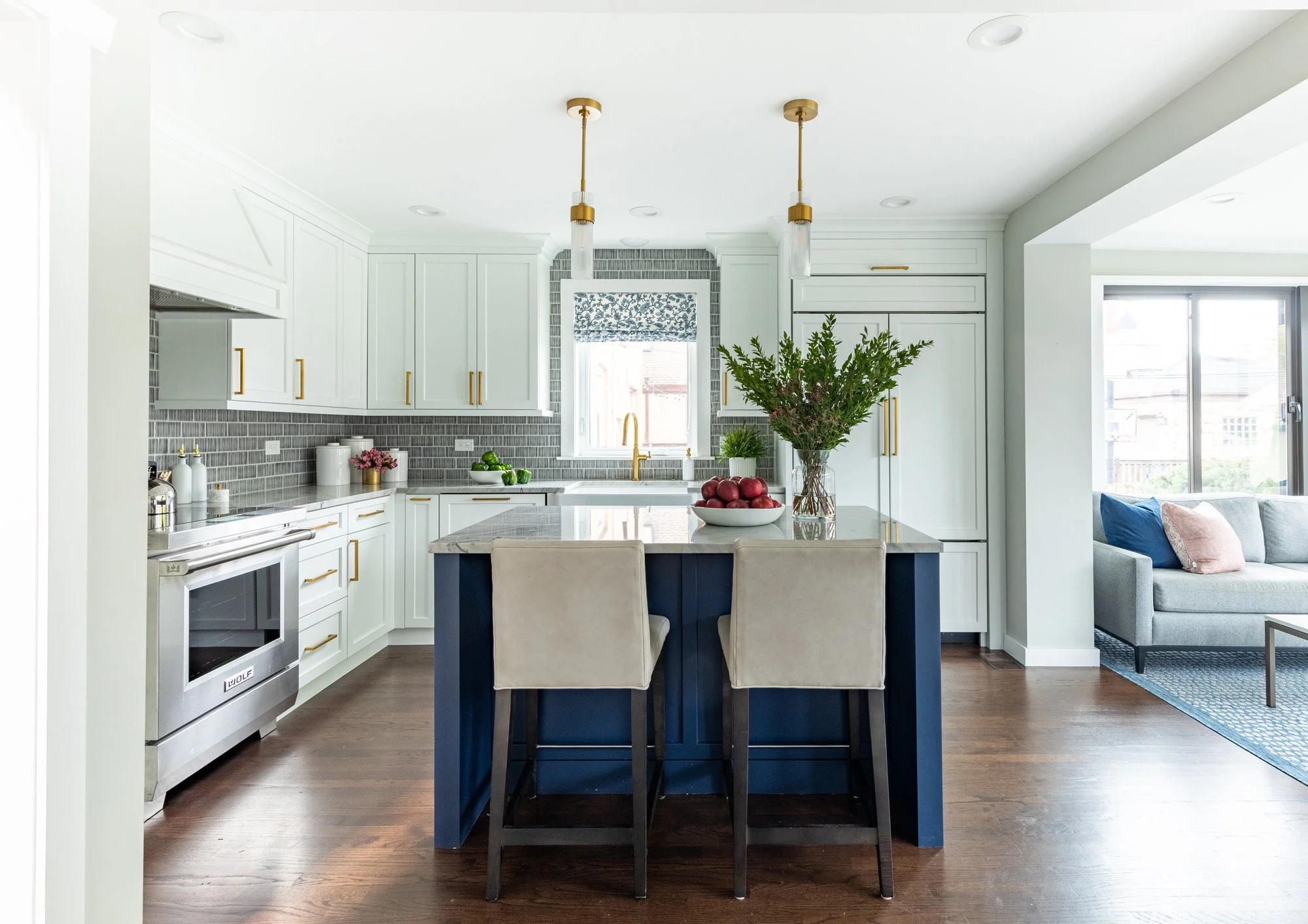 White and navy kitchen with a blue island, quartzite countertops, brass lighting, and custom cabinetry in a North Edgebrook Chicago home renovation, designed by Wendy Nobriga Interiors.