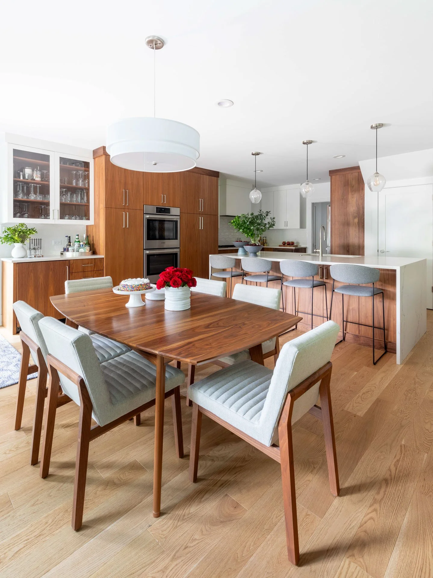 Wildwood Chicago IL open kitchen and dining area with wood table, upholstered chairs, and modern light fixtures, designed by Wendy Nobriga Interiors.