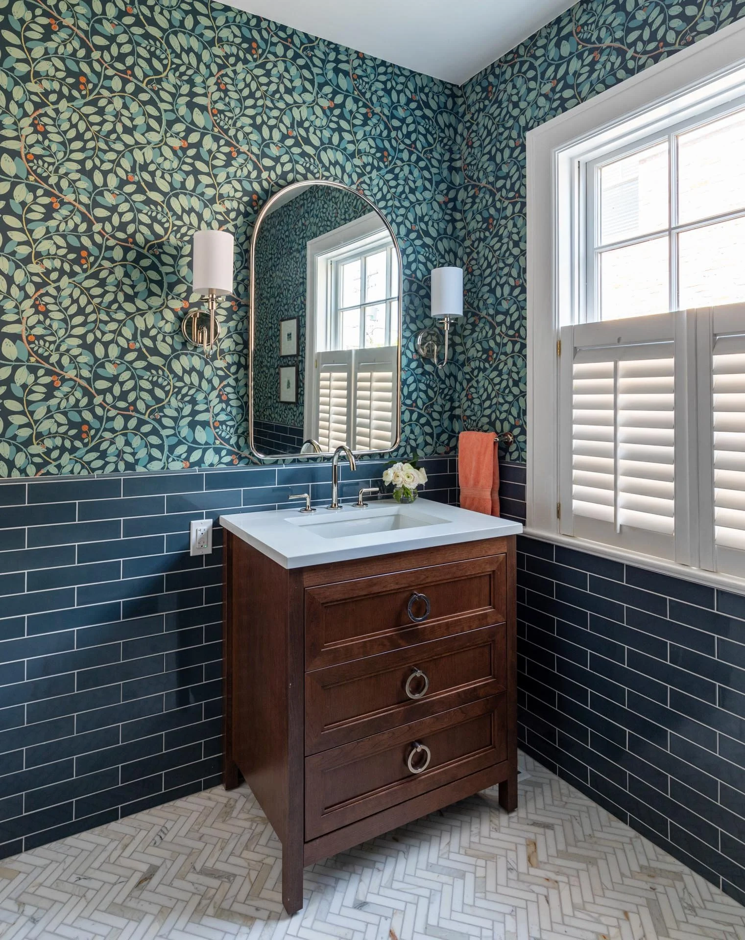 Lake Forest IL bathroom with wood vanity, blue subway tile wainscoting, botanical wallpaper, and herringbone marble floor, designed by Wendy Nobriga Interiors.