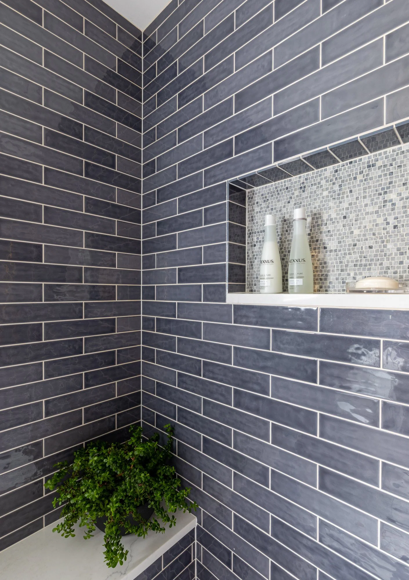 Custom shower bench and recessed shower niche in a North Edgebrook Chicago first-floor bathroom featuring blue ceramic wall tile, marble-tiled niche, and quartz sills, designed by Wendy Nobriga Interiors.