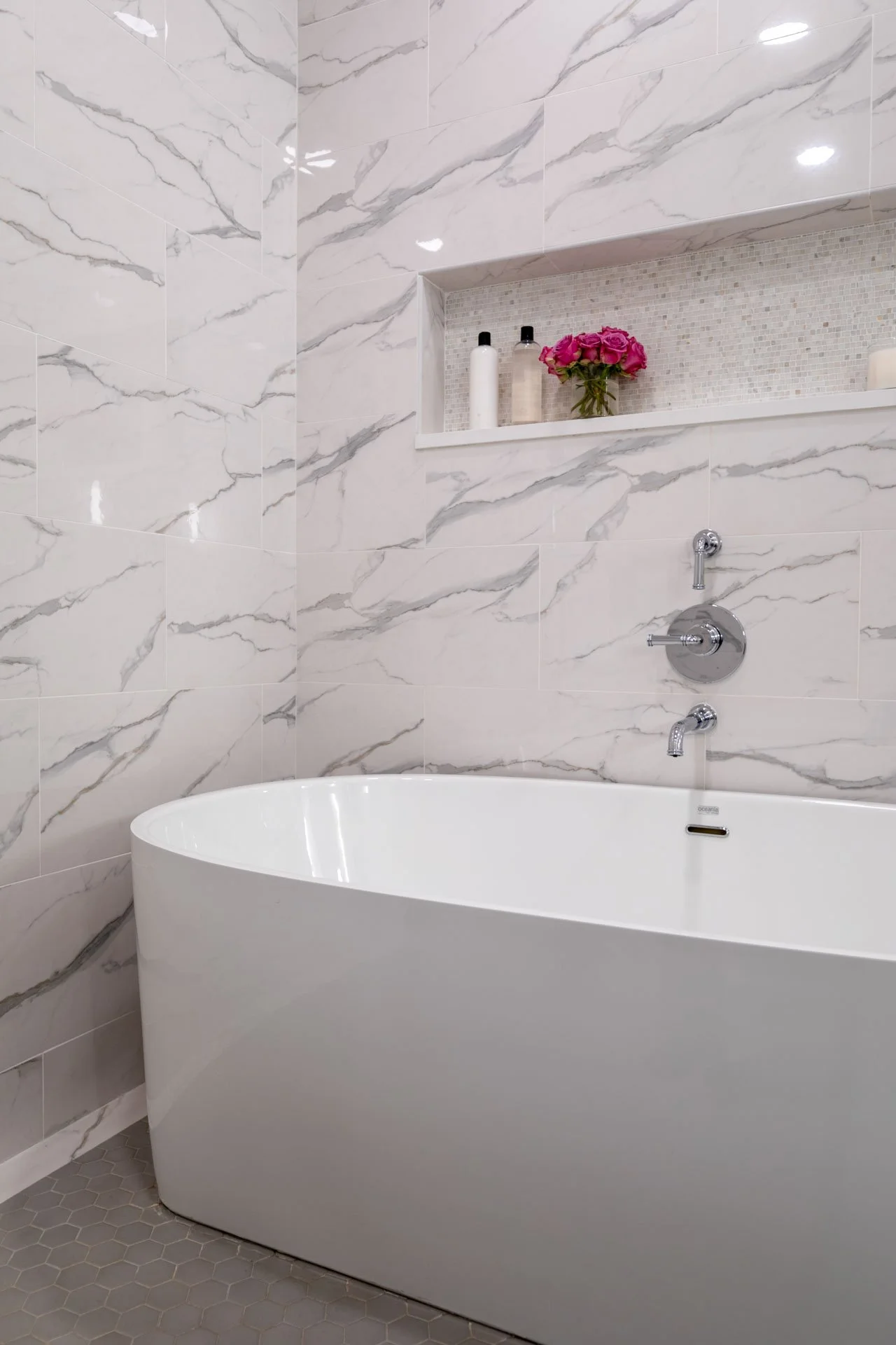 Lake View Chicago primary bathroom wet room with freestanding soaking tub, marble-look porcelain tile, and niche shelf with decor, designed by Wendy Nobriga Interiors