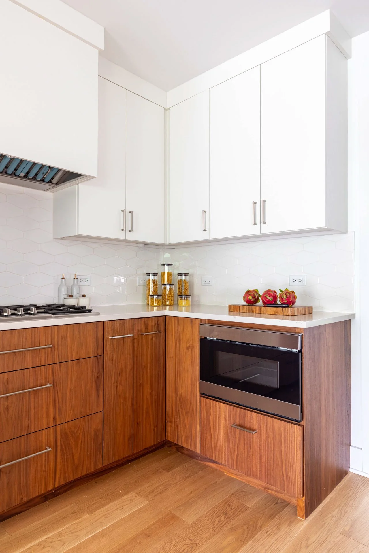 Wildwood Chicago IL kitchen corner view with mix of walnut wood and white cabinetry, quartz counters, and modern built-in oven, designed by Wendy Nobriga Interiors.