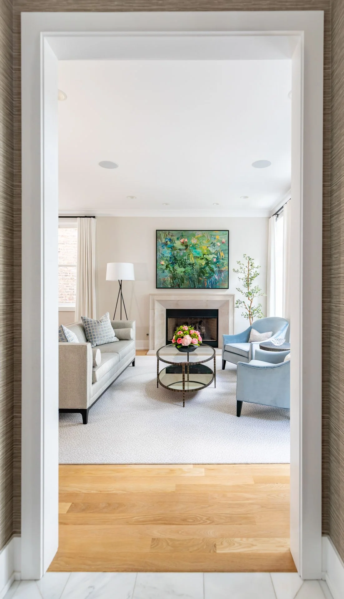 View through doorway into a Roscoe Village Chicago living room with sofa, blue chairs, and fireplace, designed by Wendy Nobriga Interiors.