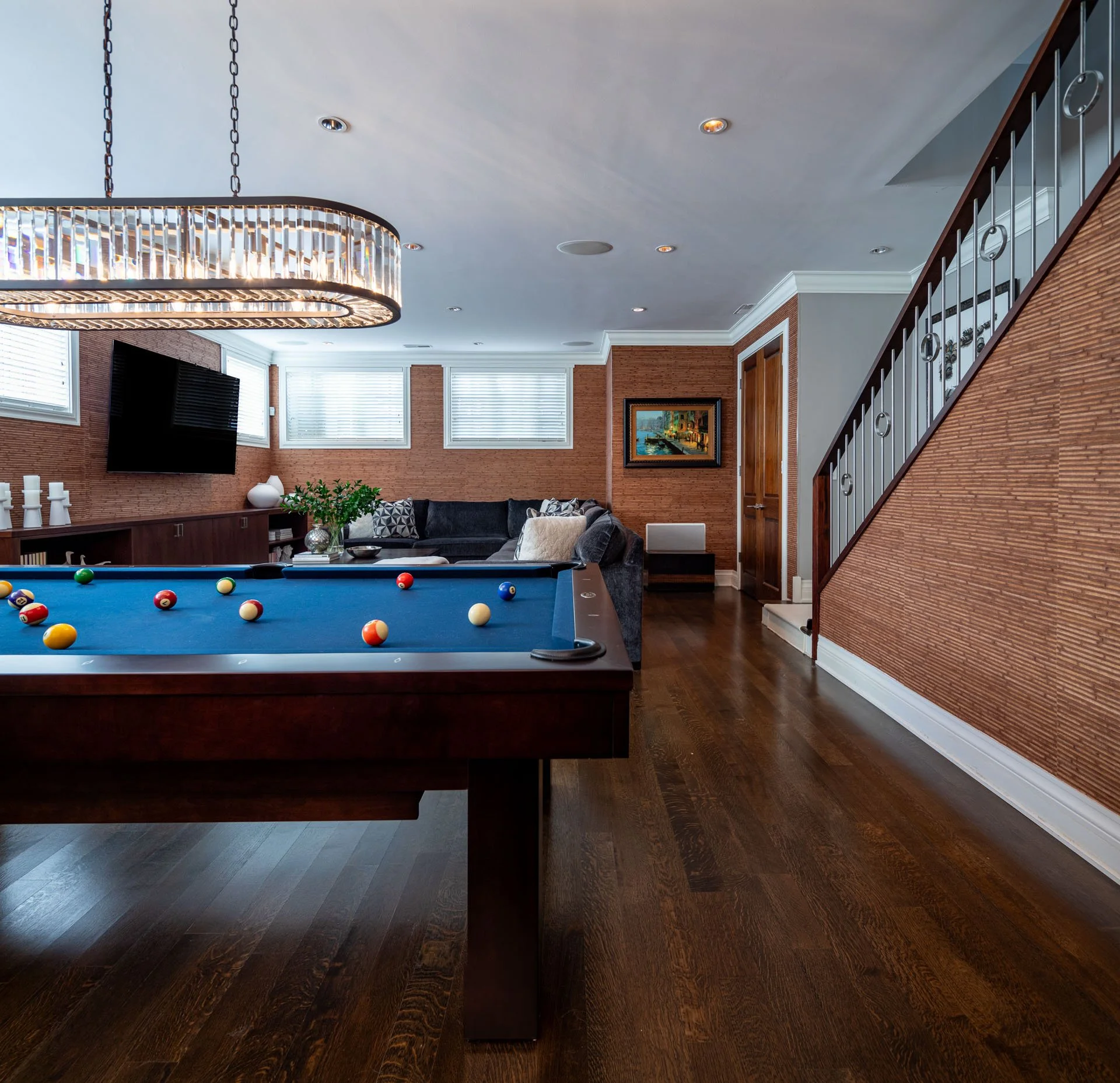 Roscoe Village Chicago basement view with pool table, sectional sofa, and staircase with iron railing, designed by Wendy Nobriga Interiors.