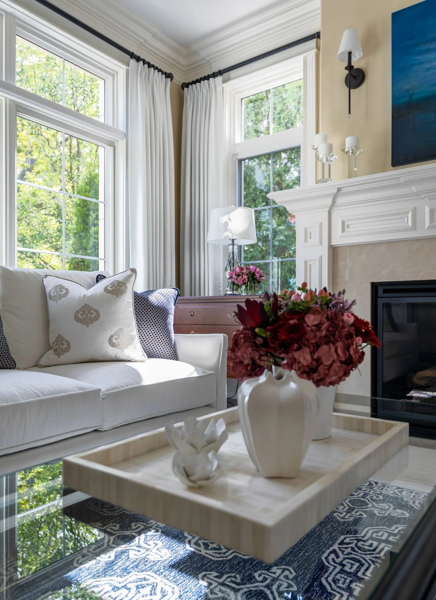 Lincolnwood IL living room detail with white sofa, accent pillows, coffee table with vases, and fireplace mantel, designed by Wendy Nobriga Interiors.