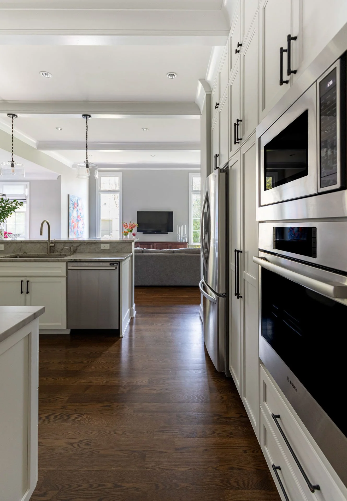 La Grange IL kitchen with stainless steel refrigerator, wall oven, quartzite counters, and view to family room by Wendy Nobriga Interiors.