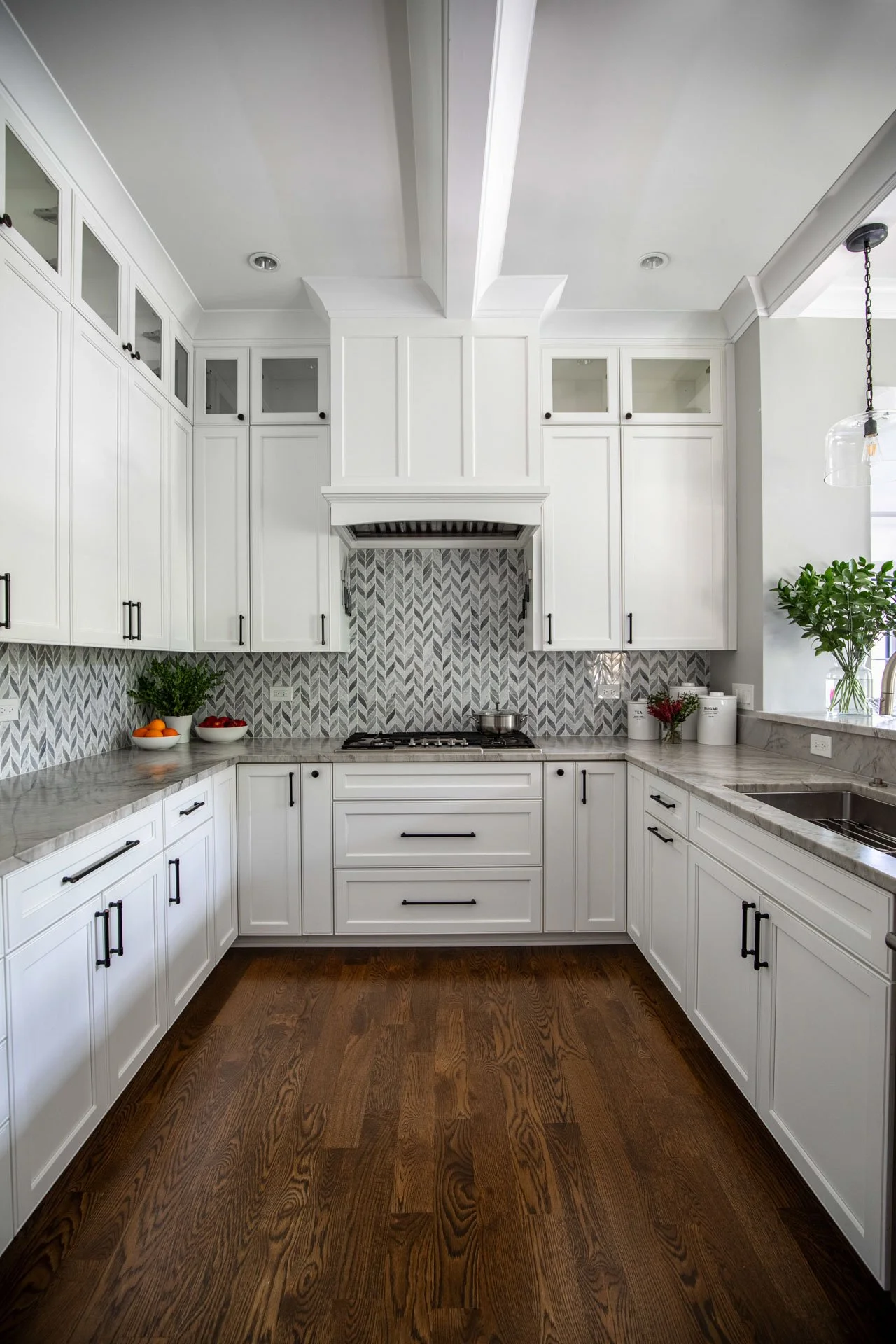 La Grange IL kitchen featuring custom white range hood, chevron tile backsplash, quartzite counters, and white cabinetry by Wendy Nobriga Interiors.