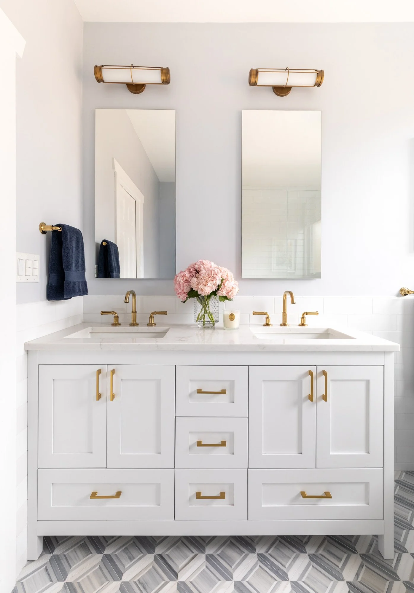 Custom white double vanity in a North Edgebrook Chicago primary bathroom featuring quartz countertops, brass plumbing fixtures, and modern sconces, designed by Wendy Nobriga Interiors.