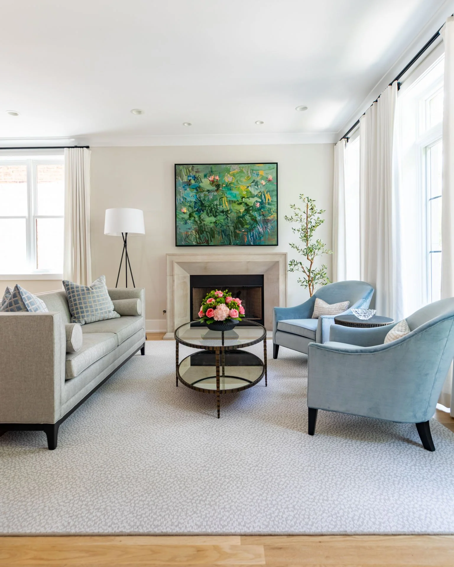 Full living room view featuring sofa, blue armchairs, fireplace, and abstract artwork in Roscoe Village, Chicago, by Wendy Nobriga Interiors.