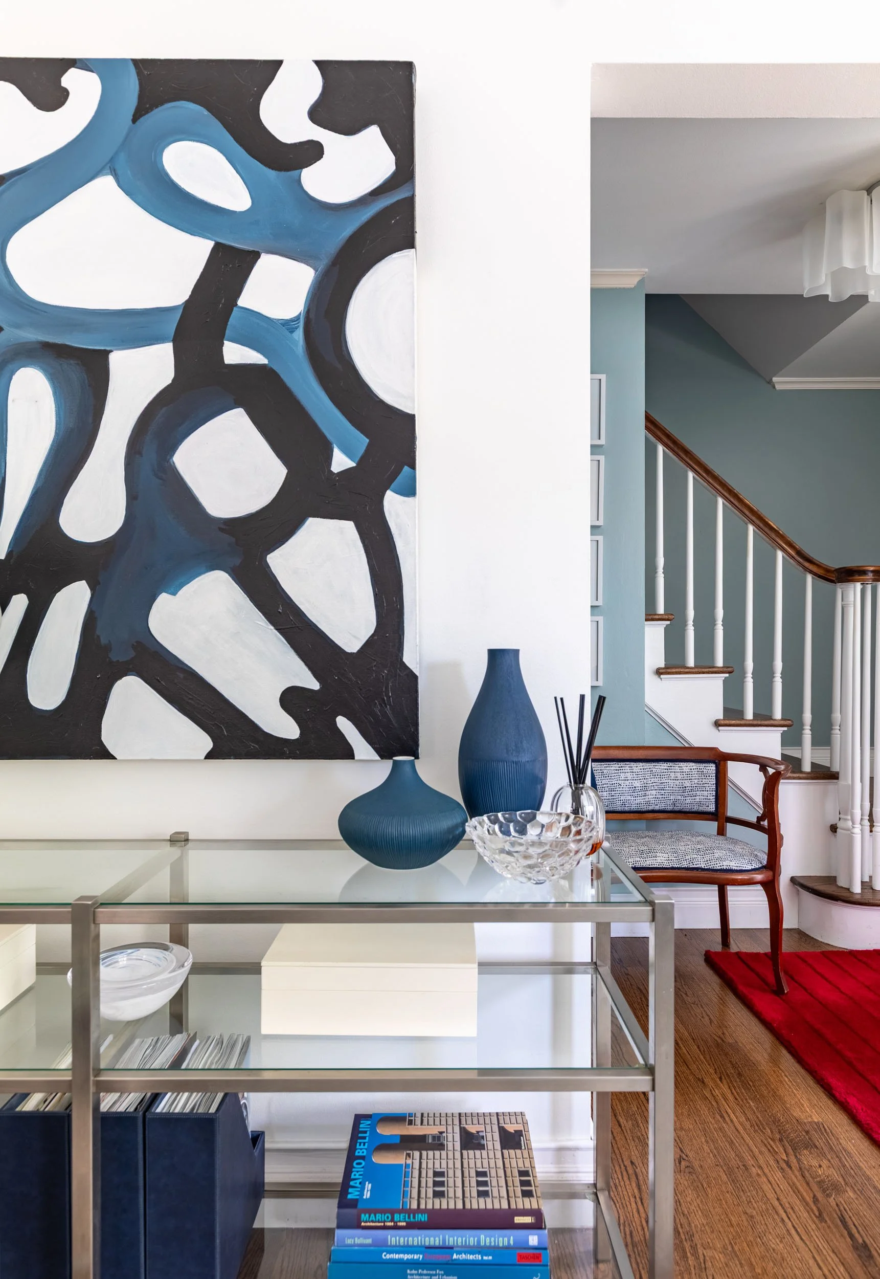 Modern living room console in Edgebrook, Chicago, IL with layered artwork, decorative objects, and glass shelving. Design by Wendy Nobriga Interiors.