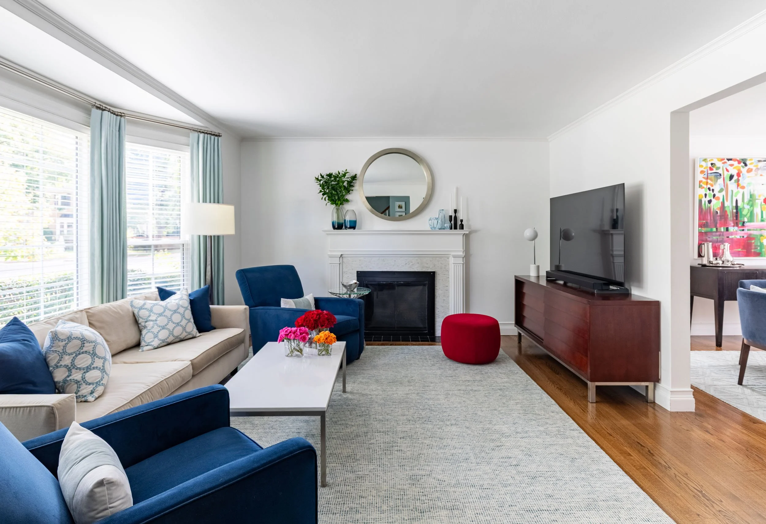 Living room in Edgebrook, Chicago, IL with modern seating, fireplace, wall-mounted TV, and layered blue accents. Design by Wendy Nobriga Interiors.