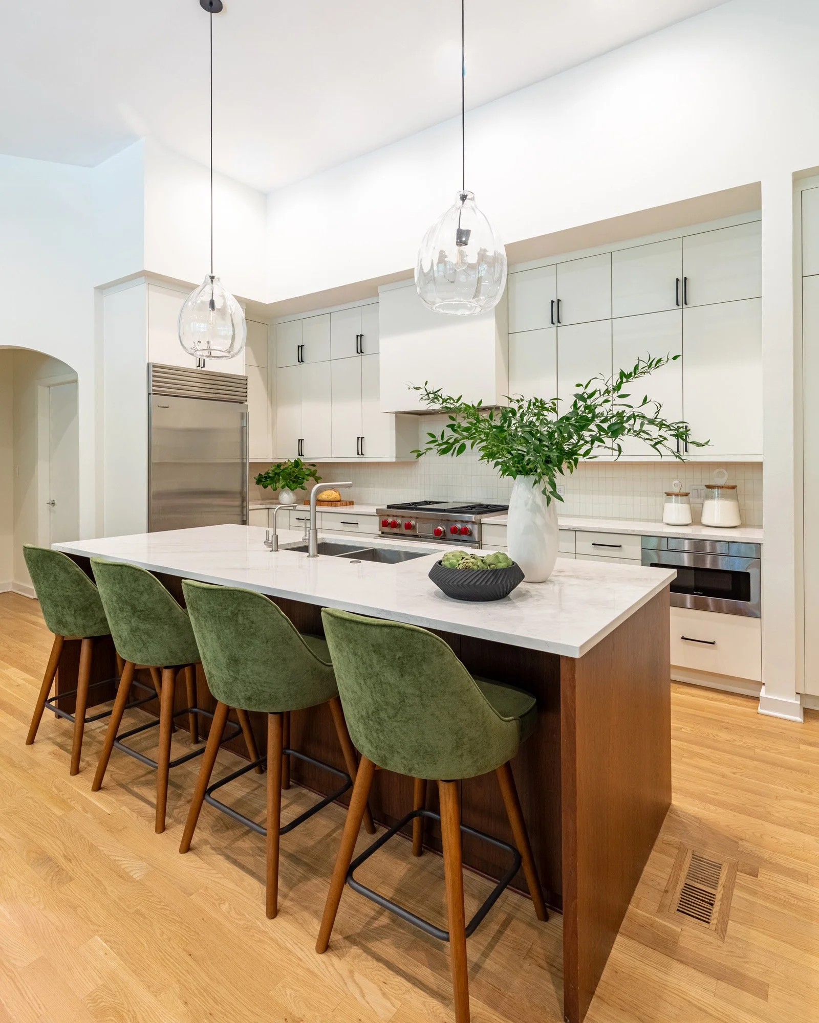 Lincoln Park, Chicago modern kitchen with walnut island, white quartz countertops, slim shaker cabinetry, and green upholstered barstools.