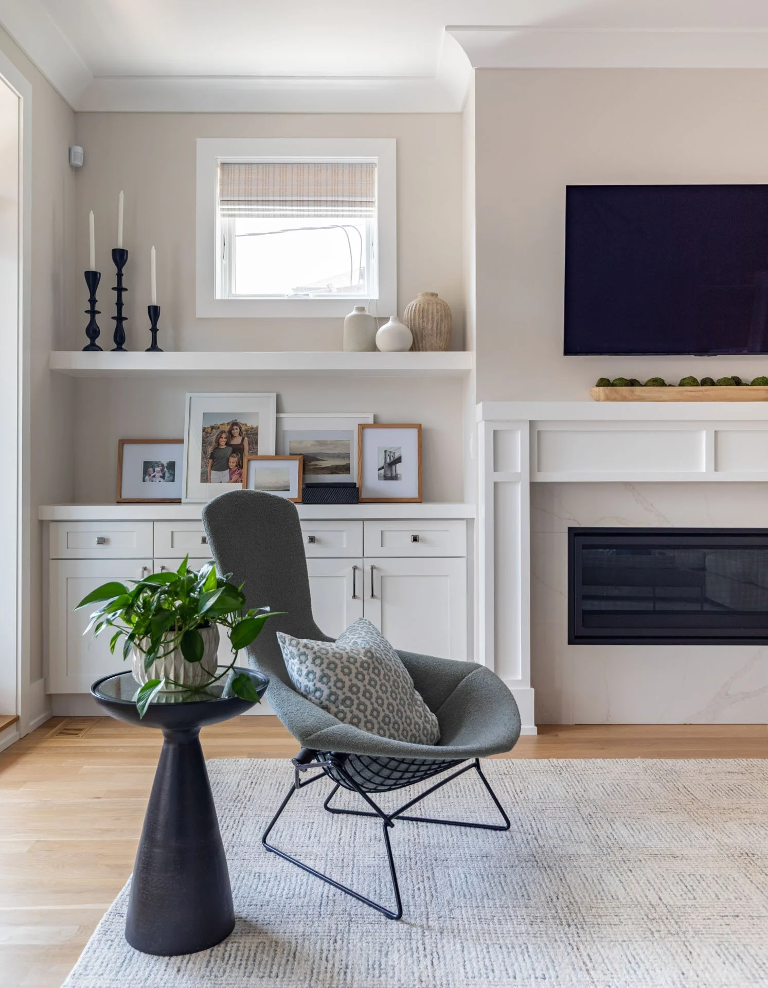Roscoe Village Chicago family room detail with modern accent chair, black side table with greenery, and fireplace built-ins styled with art and candles, designed by Wendy Nobriga Interiors.