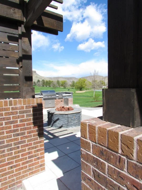 dark stone and wood finishes with brick wall and light square paver patio