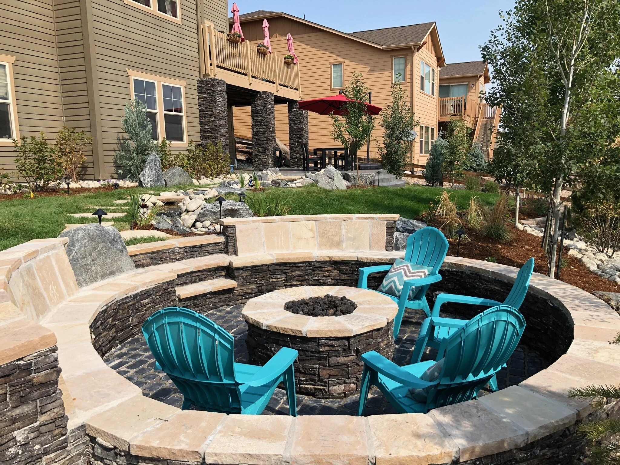 enclosed paver patio with stone wall and fire pit