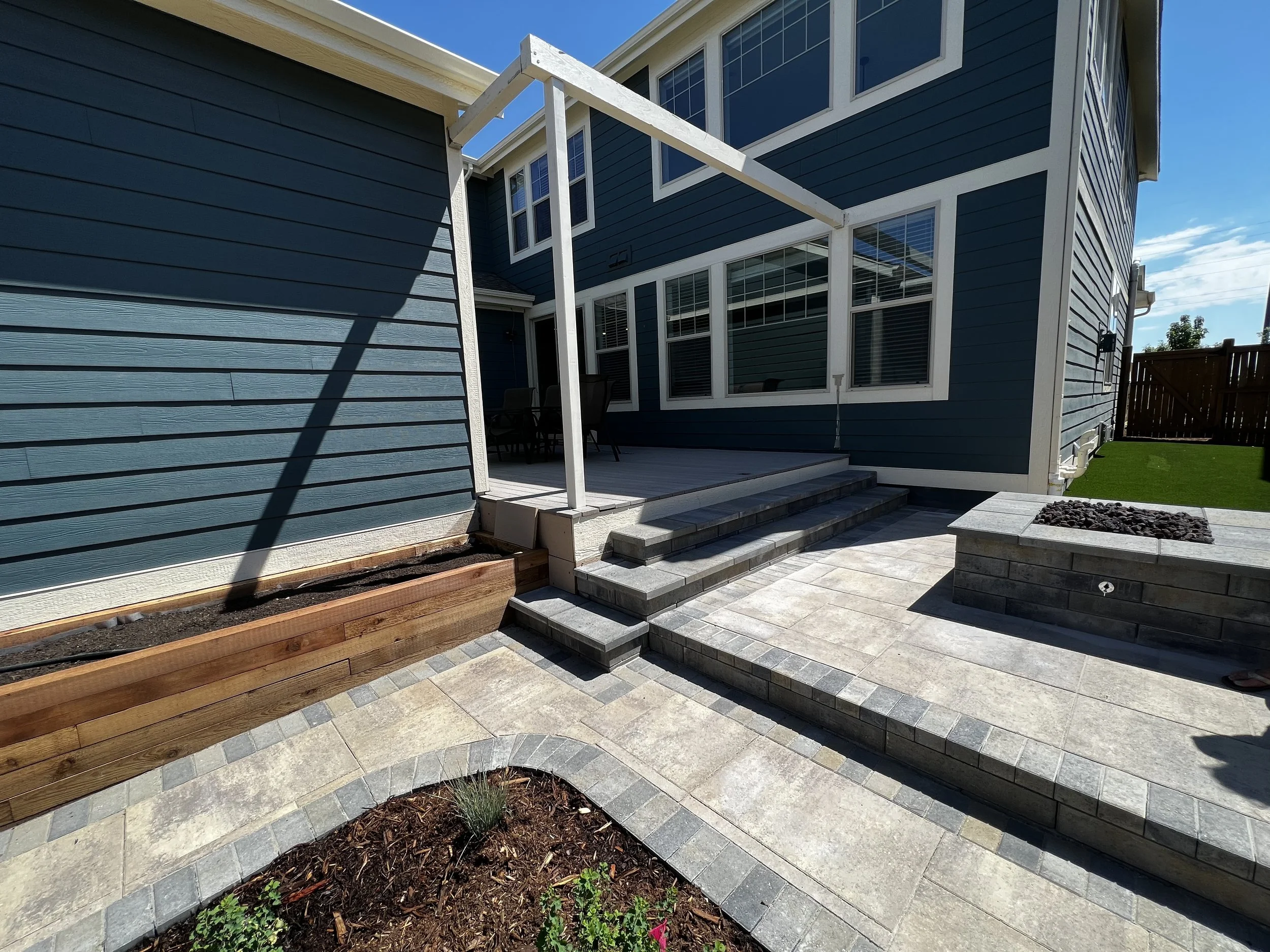 custom paver patio outlining garden and fire pit