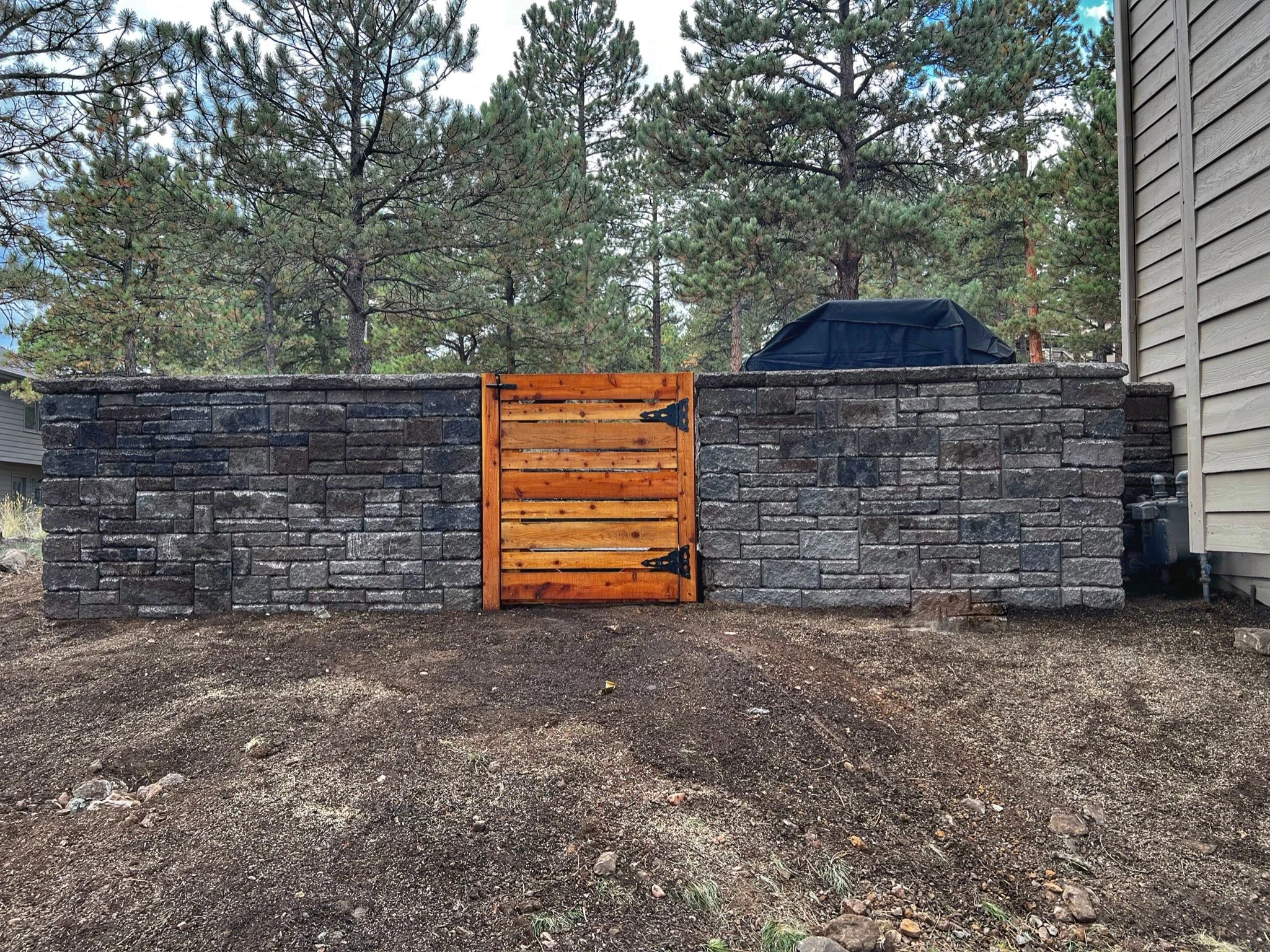large custom stone retaining wall with natural cedar door