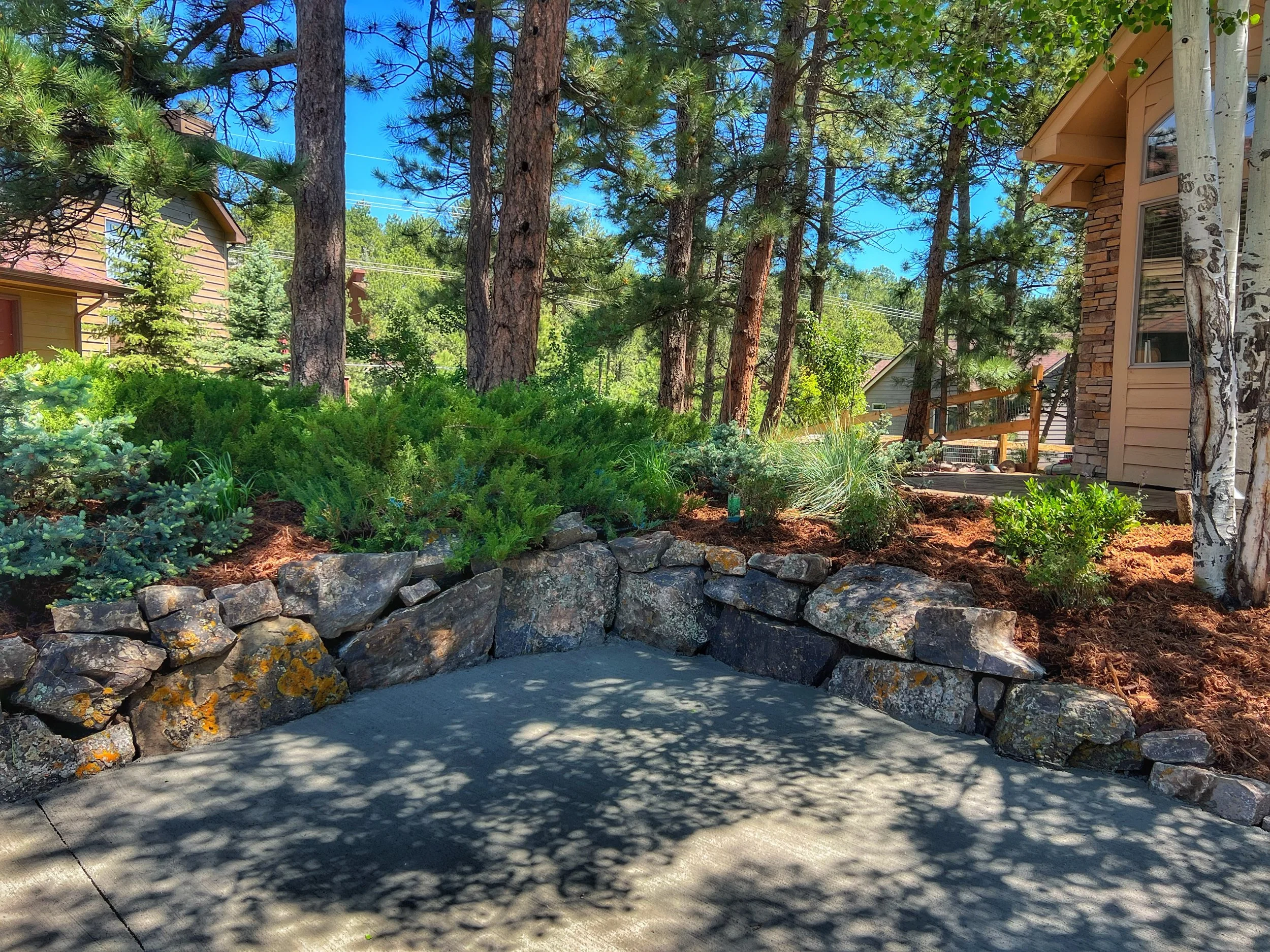 beautiful mountain backyard with custom boulder wall and garden