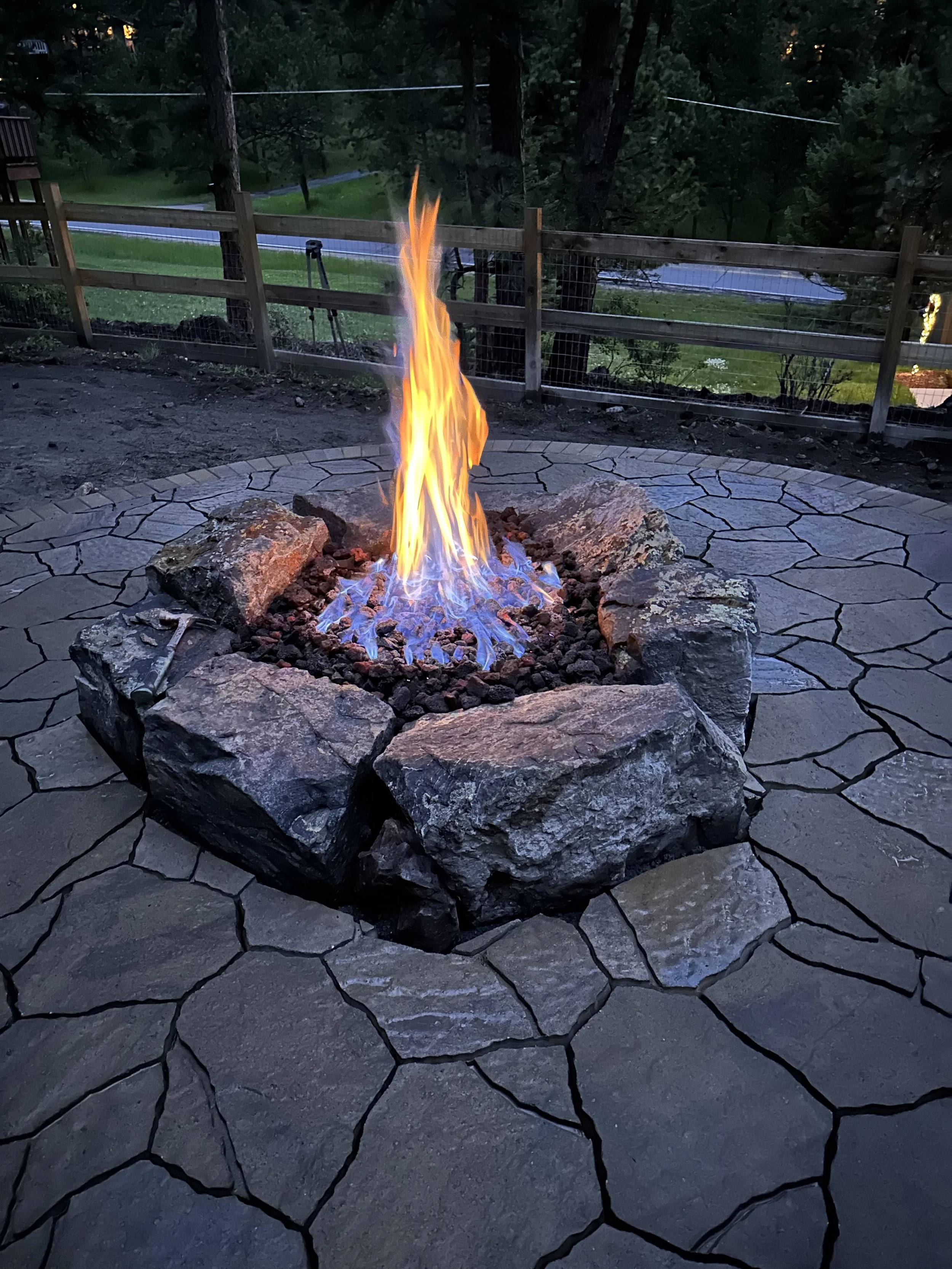 natural boulder fire pit surrounded by custom stone patio