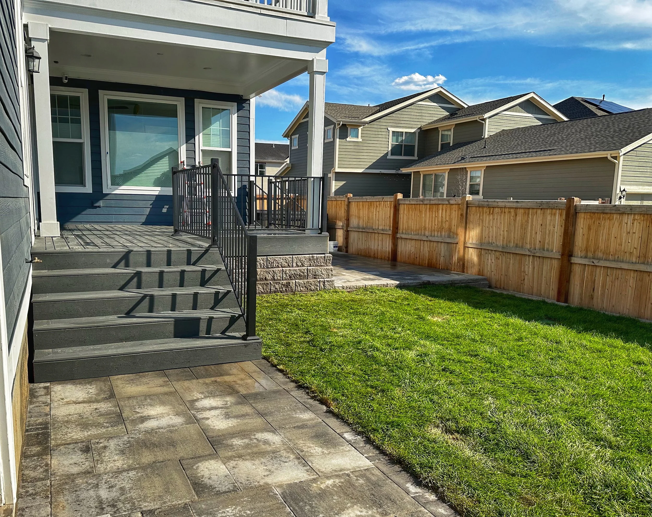 grey trek deck with iron railings and paver walkway