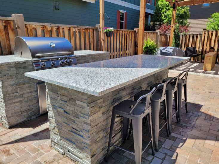 large outdoor granite counter top with stone and stainless steel grill