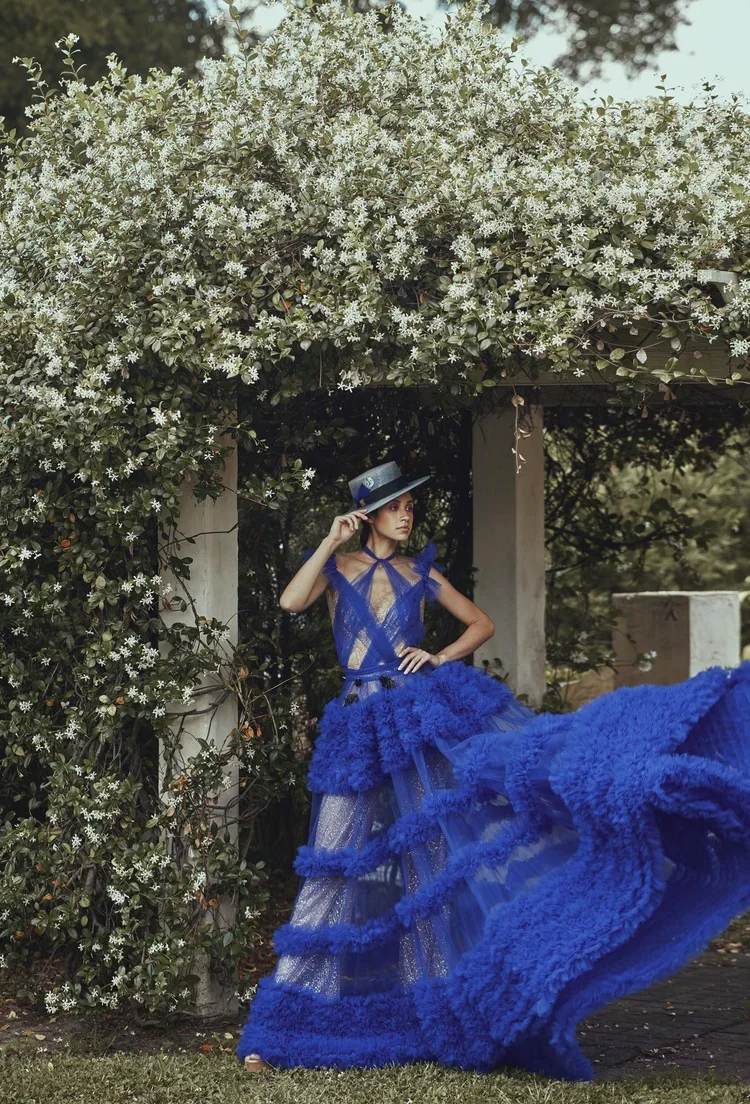 Model in dramatic blue gown under arbor