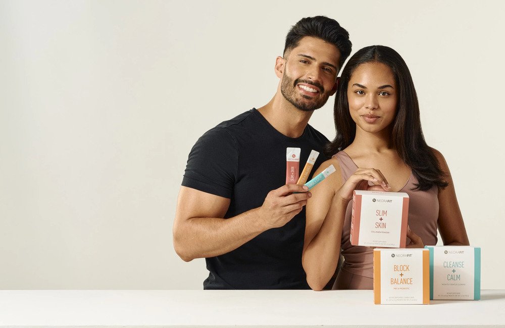  Man and woman posing with wellness supplement products against a neutral studio background 