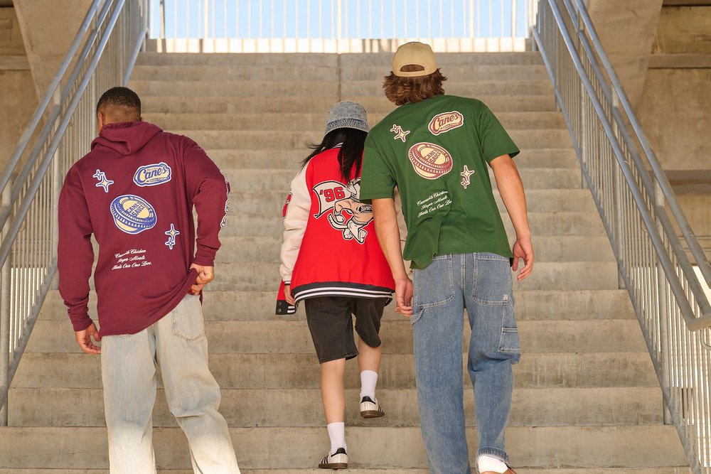  Three people wearing colorful branded streetwear walking up outdoor stadium stairs 