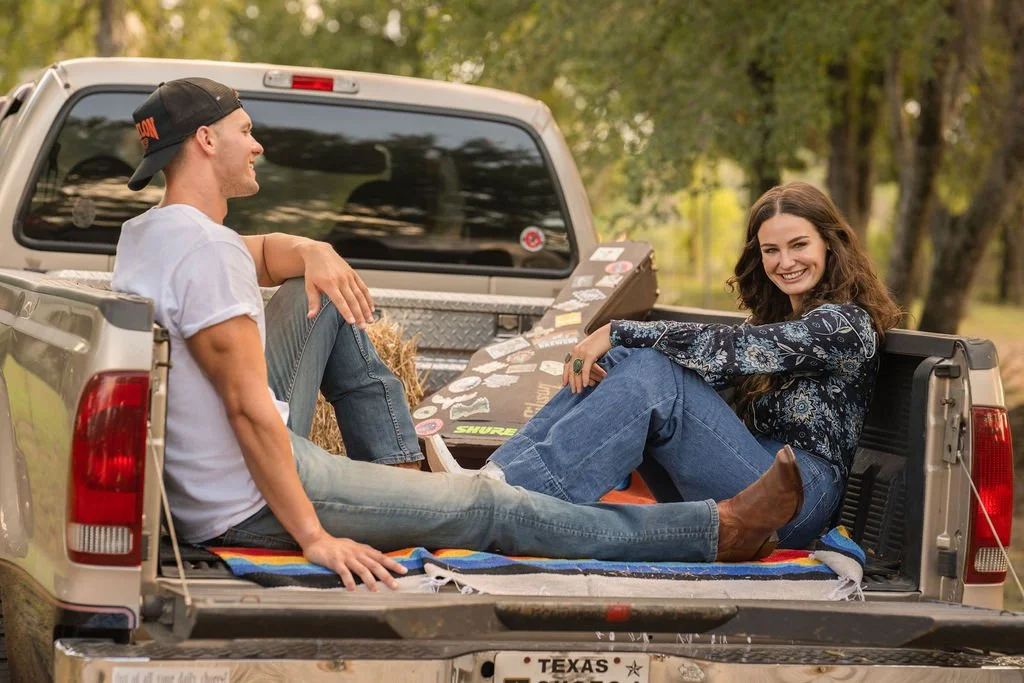 Man and woman relaxing in the bed of a pickup truck