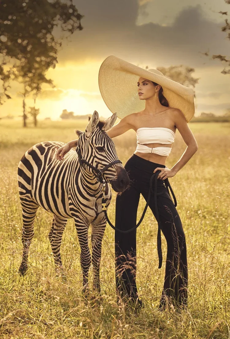 Fashion model posing with zebra at sunset