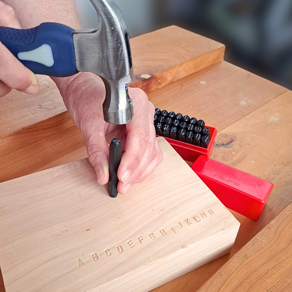 Using an alphabet punch and hammer to stamp permanent letters into timber for literacy and Technology learning