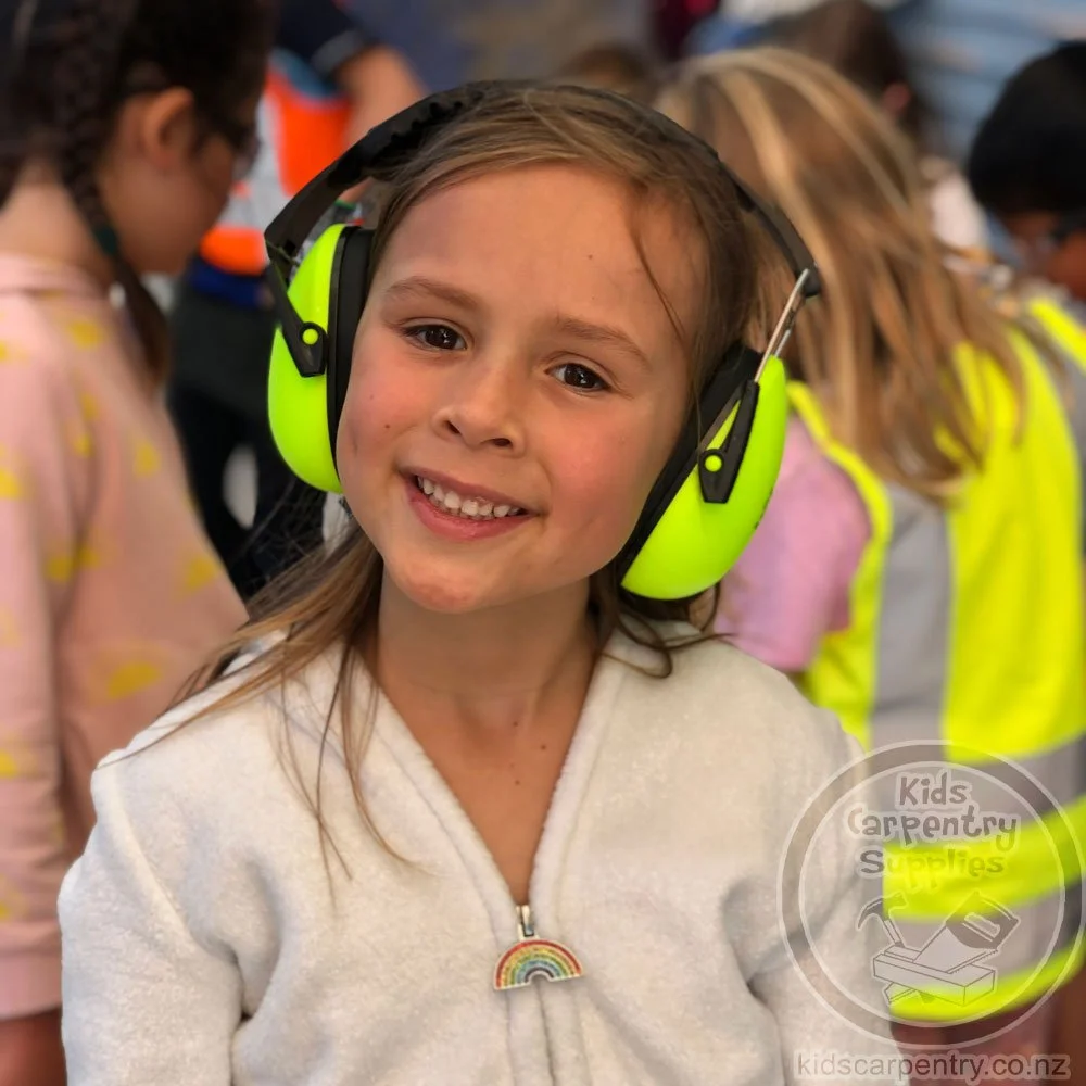 Front view of young girl wearing adjustable child sized yellow hearing protection earmuffs