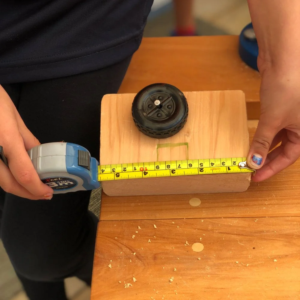 Young hands using a tape measure to measure wood for a DIY carpentry project