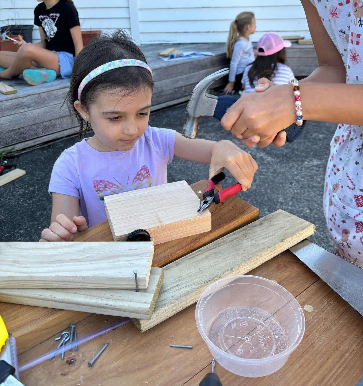 Girls Woodworking Using Pliers to Hold Nail for Hammering.