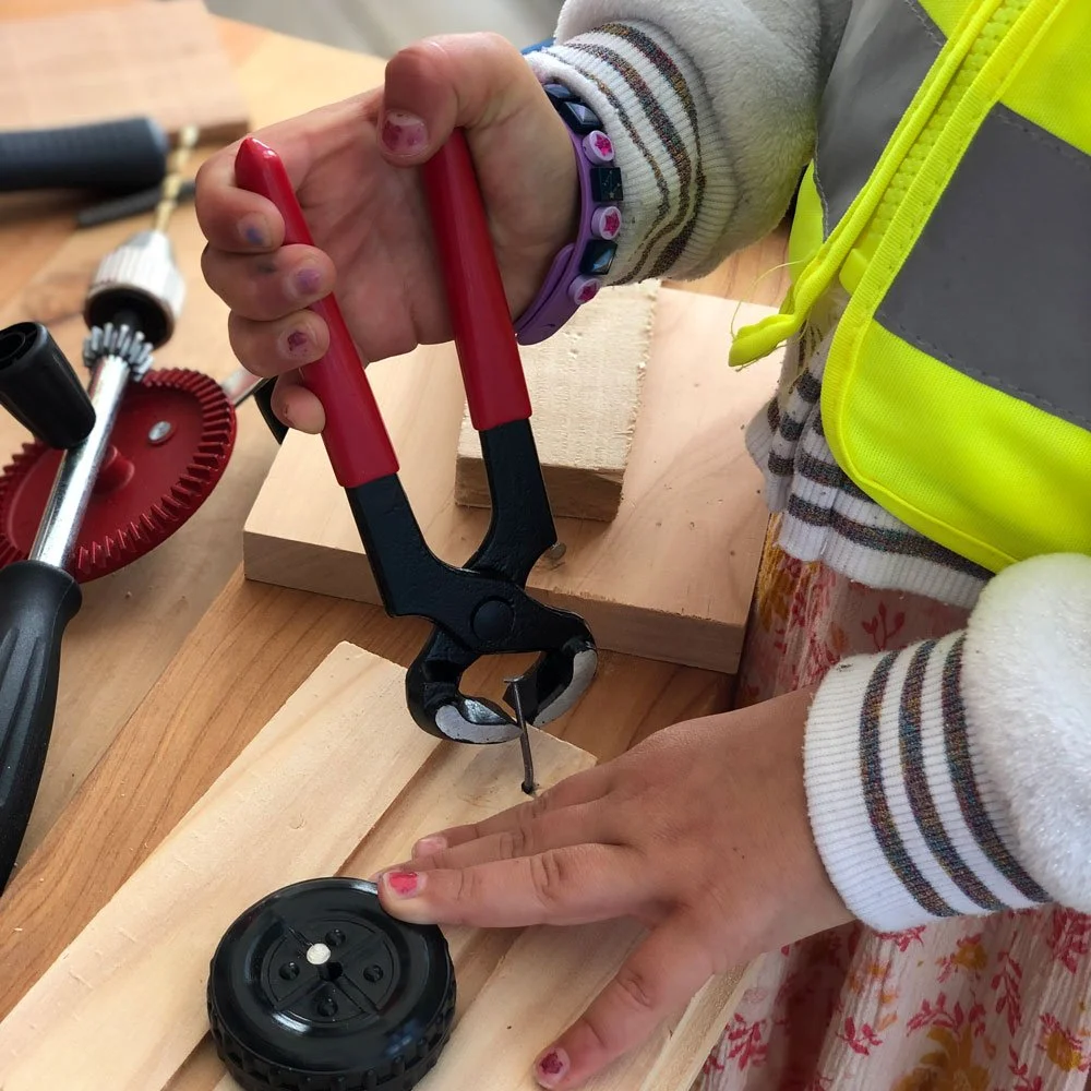 Student using nail remover pliers to safely pull out a nail in a school carpentry project