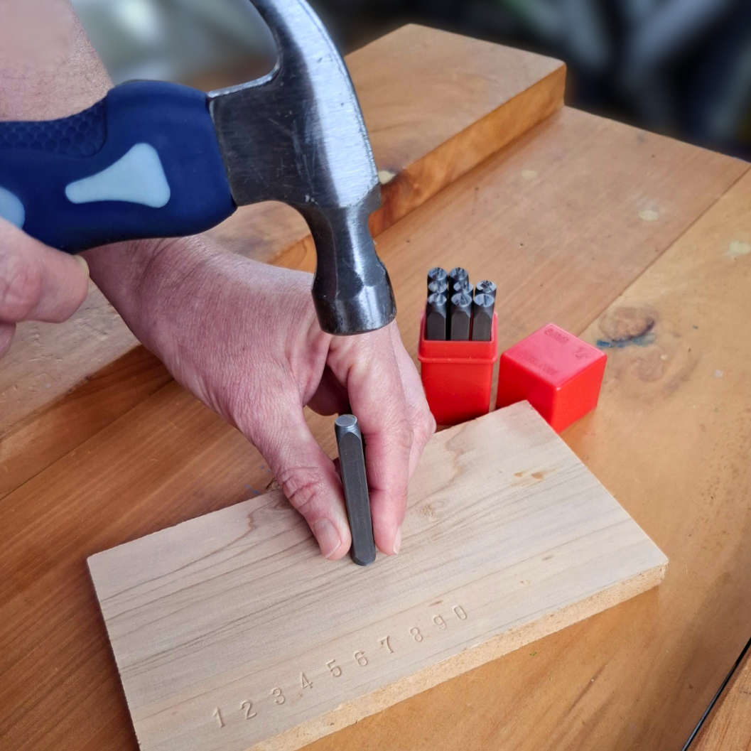 Child using a steel number punch to develop fine motor skills and number recognition through practical hammering and carpentry activities
