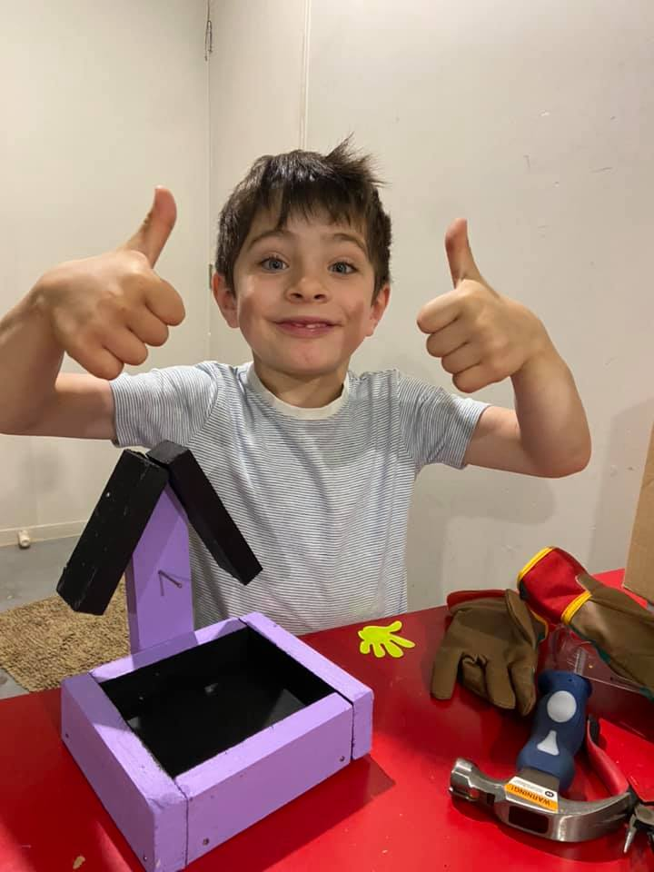 Child proudly showing a handmade wooden bird feeder built from untreated wood offcuts