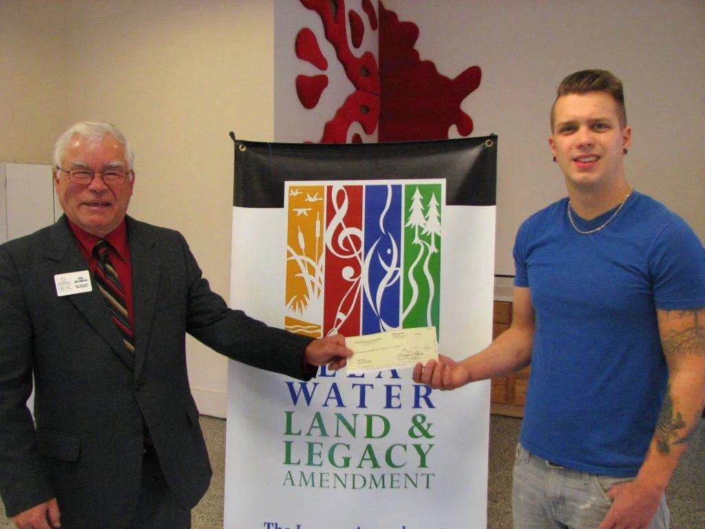 Lake Region Arts Council Board member, Jim Arvidson, presents an Artist Legacy Grant to artist Sam Norman.