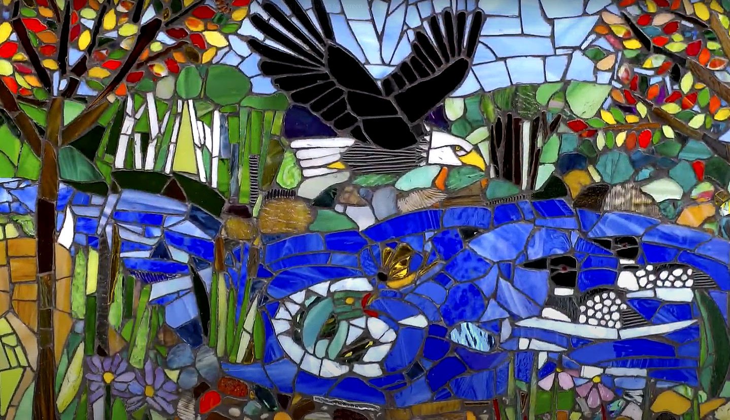  Another mosaic of bright colors depicts an eagle flying over a river with loons and a jumping fish. 