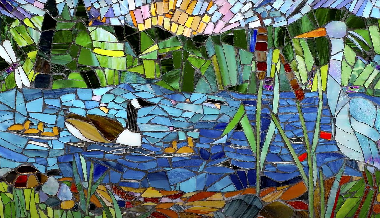  A loon with five babies swimming behind is showcased in this mosaic. 