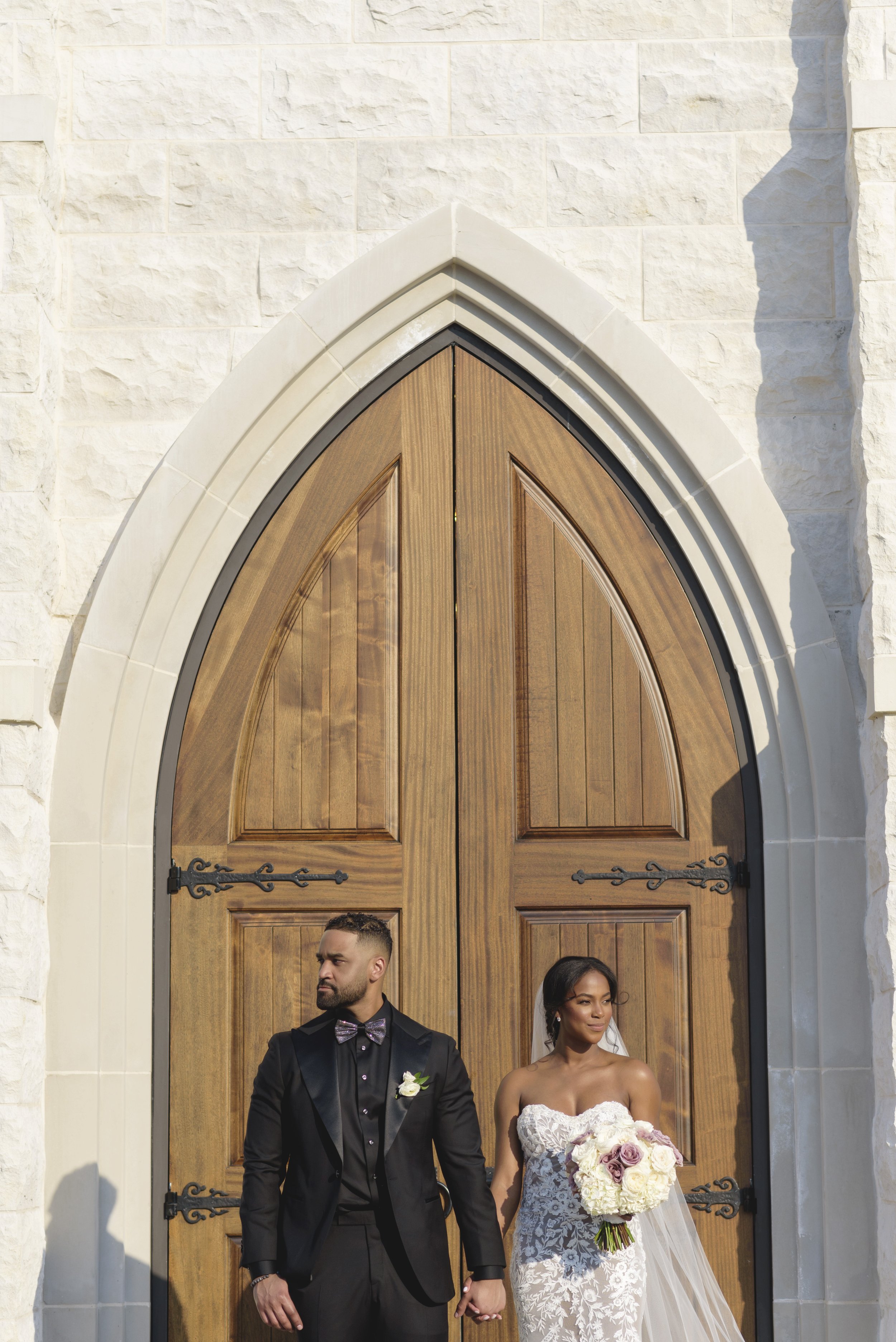 Newly wed bride and groom take photos in front of cathedral door of The Chapel on McEver Wedding Venue