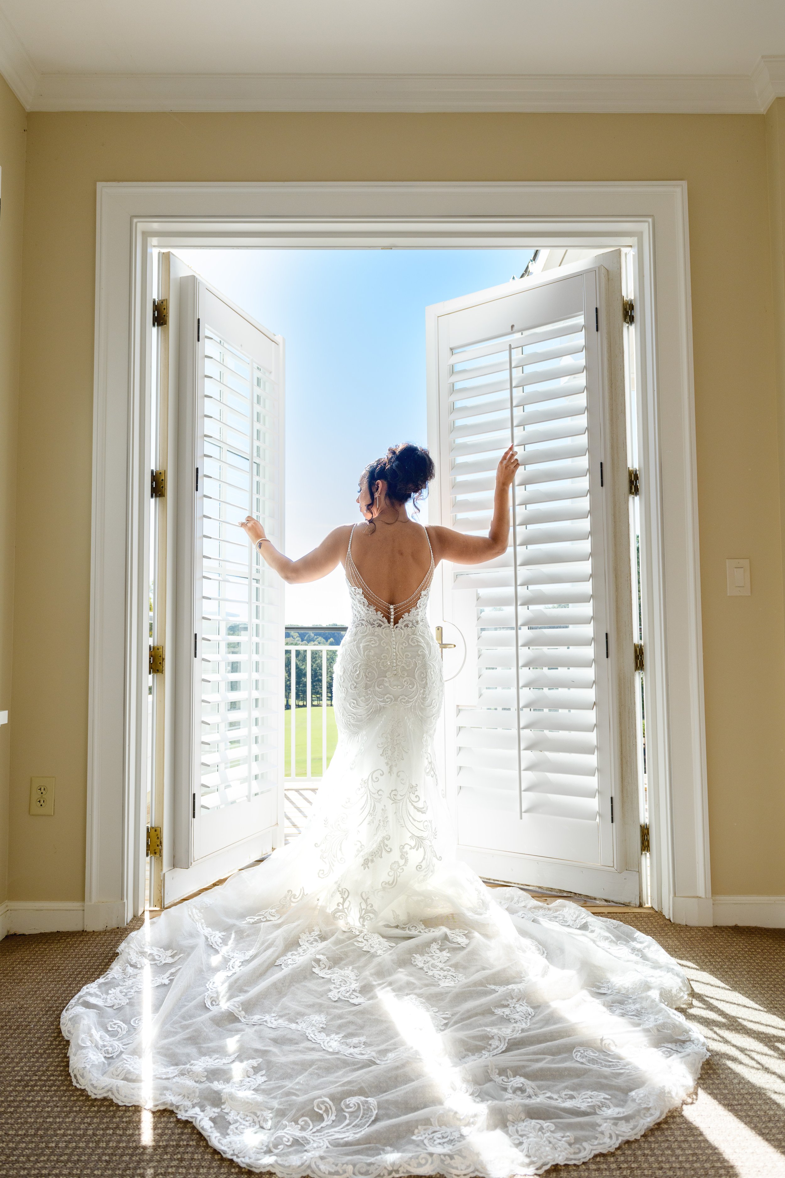 Bride to Be Stands between the bridal suite doors in her wedding gown overlooking the golf course at the The Georgia Club  moments before her first look with her father on her wedding day