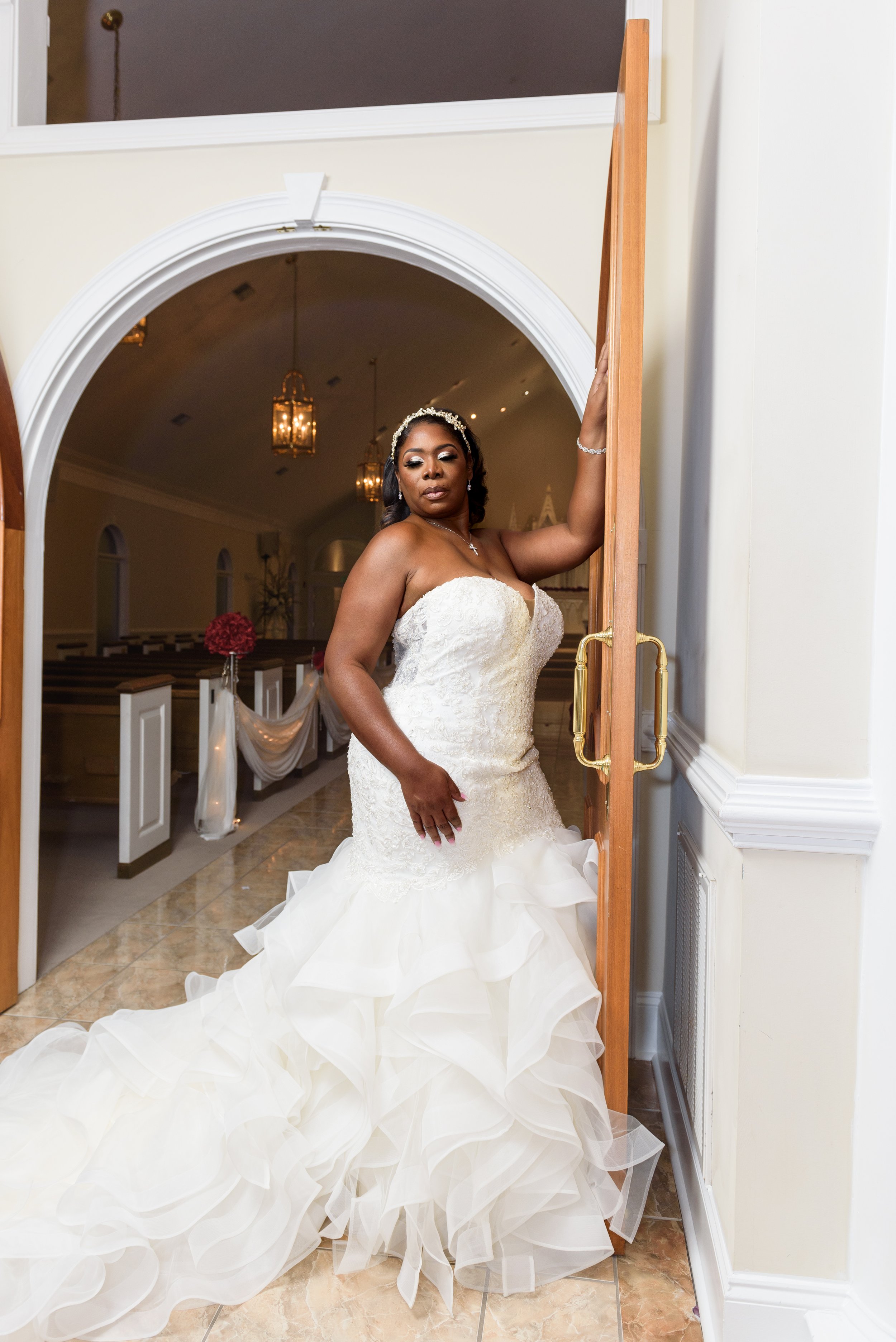 Bride in her wedding gown stands  in front of wedding chapel entrance doors of Pristine Chapel Lakeside in Jonesboro, GA