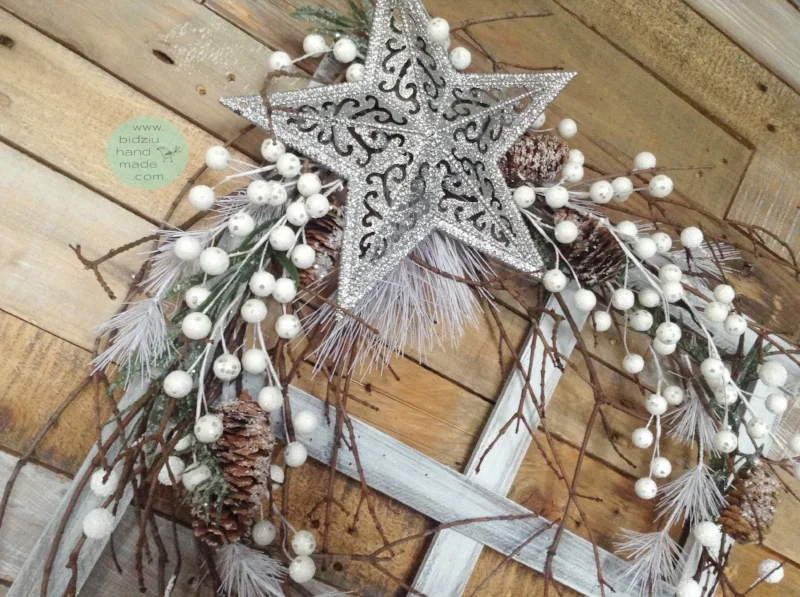 Rustic window christmas frame featuring a sparkling silver star, winter greens, natural branches, pine cones, and white berries.