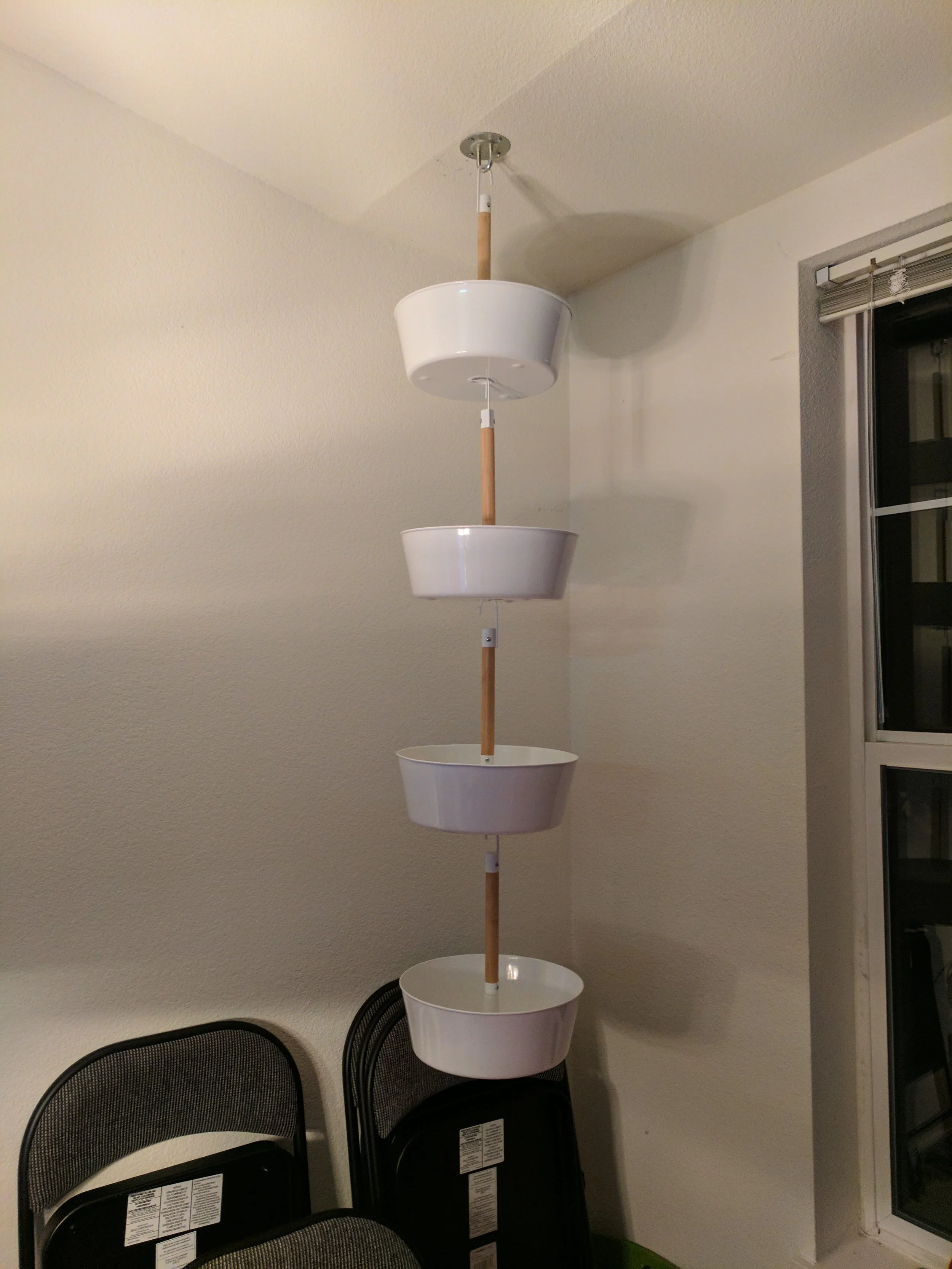 5. Use the hook of another basket, insert into the hole on the bottom of the first basket, parallel to the bar, rotate it 90 degrees, and then bring it down to rest on the bar. Hang all the baskets!