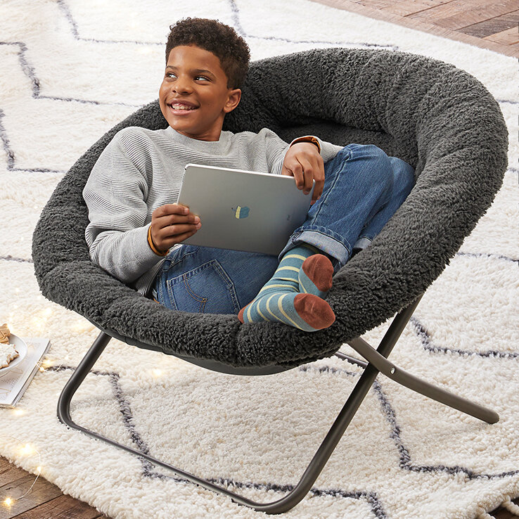 boy sitting with iPad in round chair with gray fur