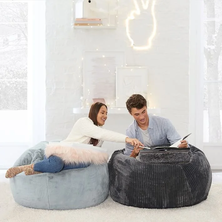  Boy and girl sitting on bean bag chairs looking at books 