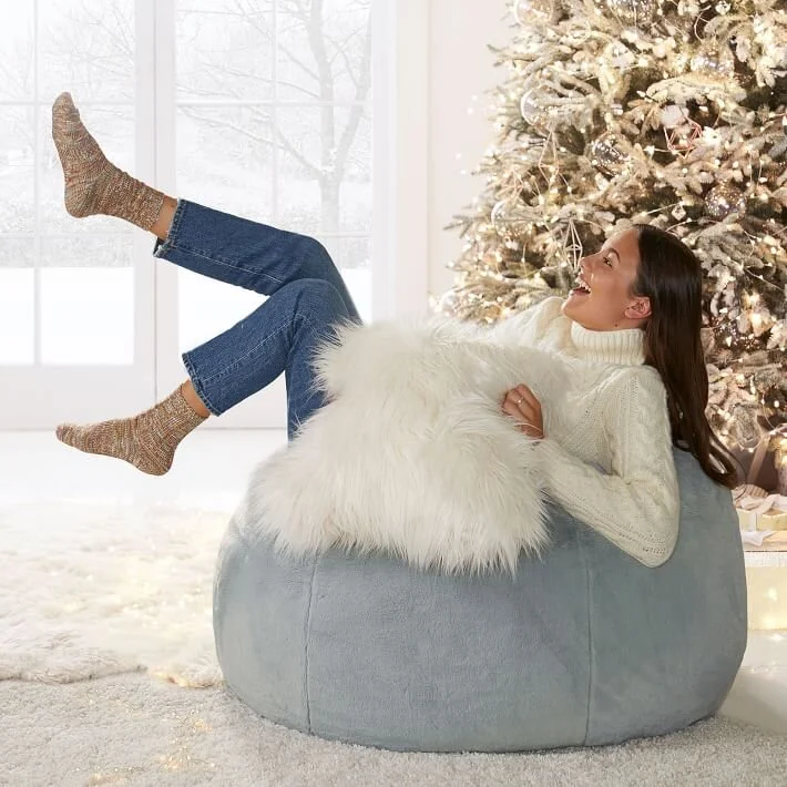  Girl sitting on gray bean bag chair in front of a Christmas Tree 