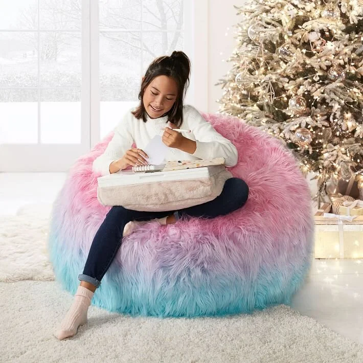  Girl sitting on a bean bag chair in front of Christmas tree 