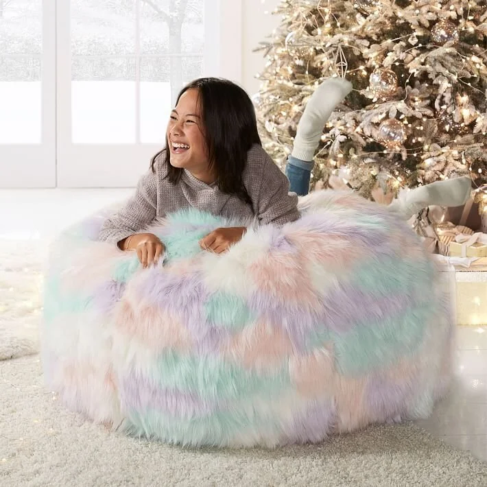  Girl laying on a pastel bean bag chair in front of a Christmas tree 